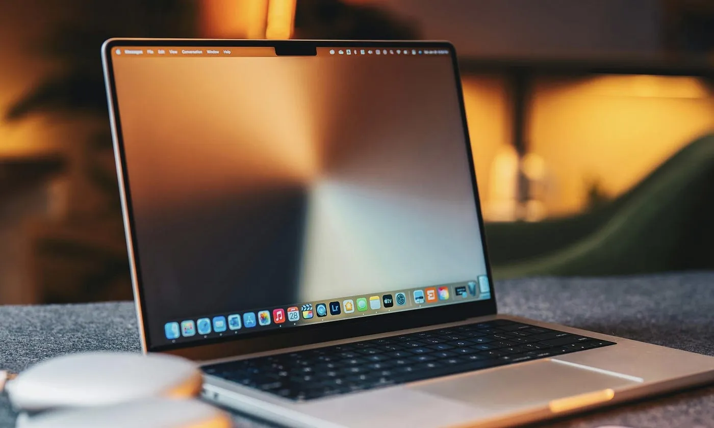 A MacBook Pro on a desk in a warm room, screen on