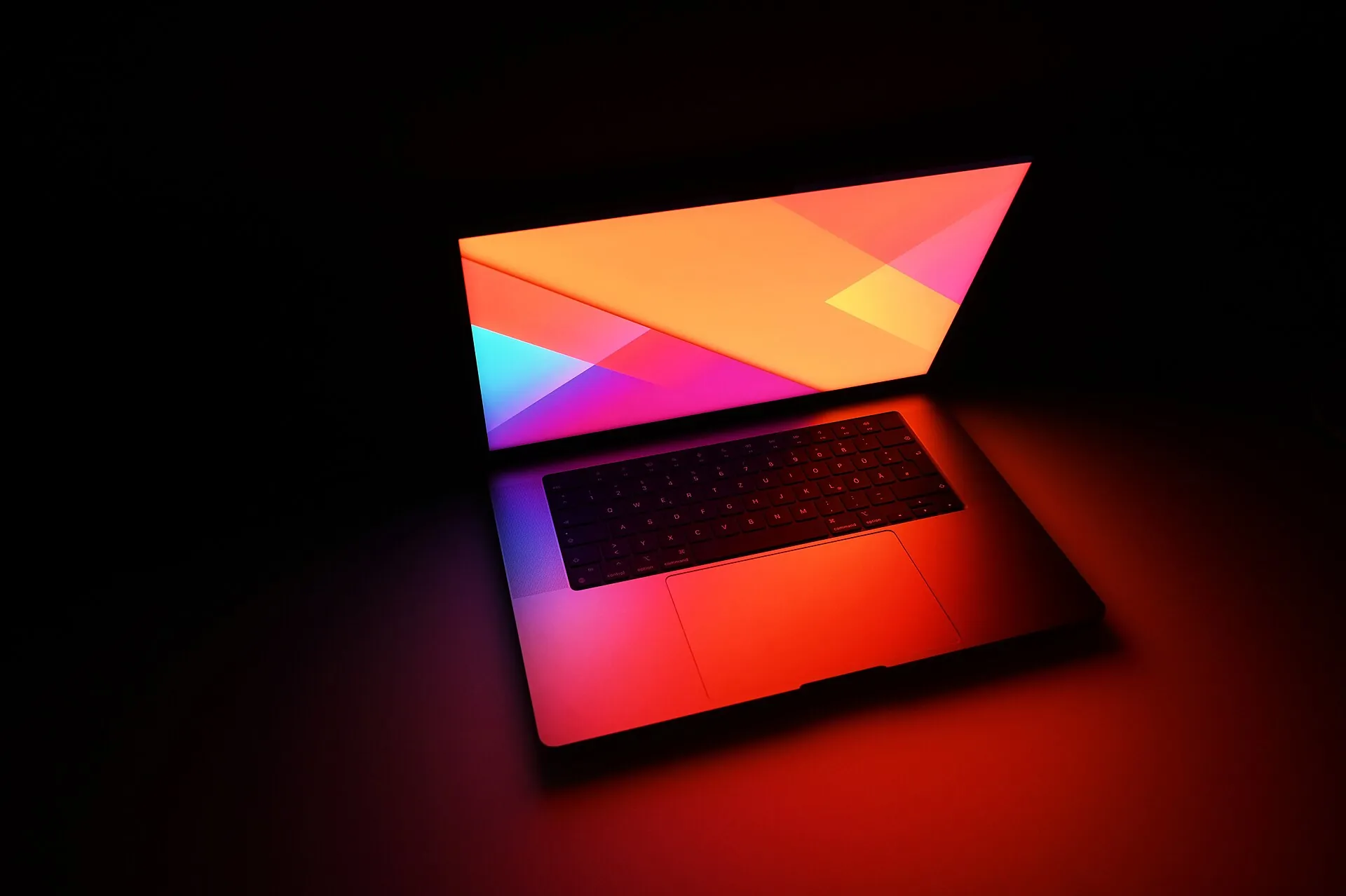 A MacBook Pro with its backlit keyboard lit in a dark room